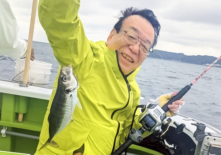 アジを釣り上げ笑顔の平田同好会顧問